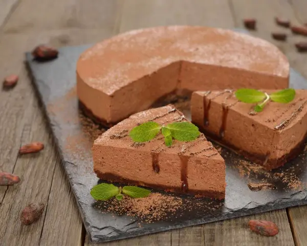 Deliziosa bavarese al cioccolato, spolverata di cacao e decorata con menta fresca. Due fette sono già pronte per essere gustate.