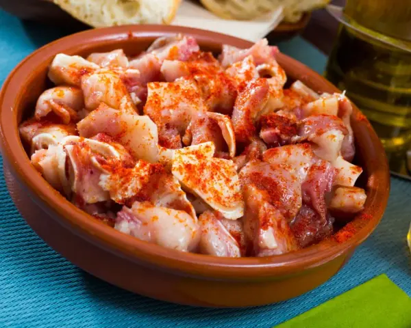 Oreja a la gallega, trozos de oreja de cerdo con pimentón en una cazuela de barro, listos para disfrutar.