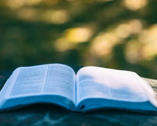 Ein aufgeschlagenes Buch liegt auf einem Tisch im Freien. Die Seiten sind mit Text gefüllt, der an Psalm 28 erinnert.