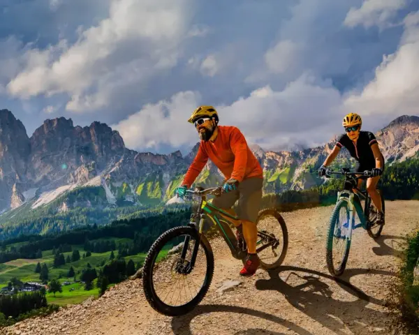 Due ciclisti si godono uno sport di montagna su sentieri sterrati con maestose vette sullo sfondo.
