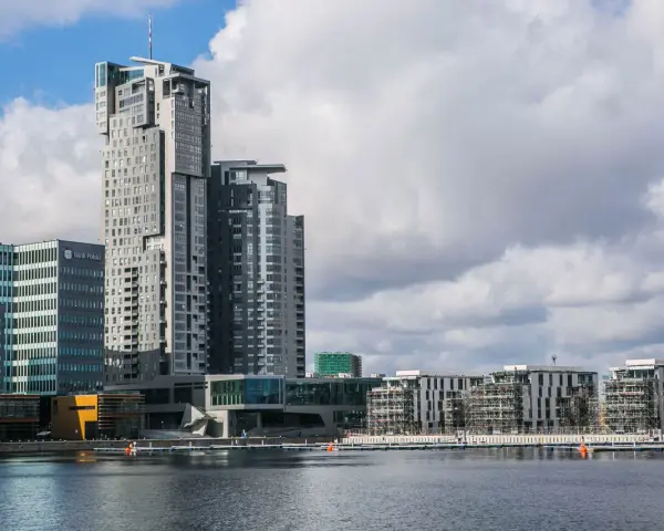 Nowoczesne budynki w Gdyni, w tym wysoki Sea Tower, nad wodą przy pochmurnym niebie.
