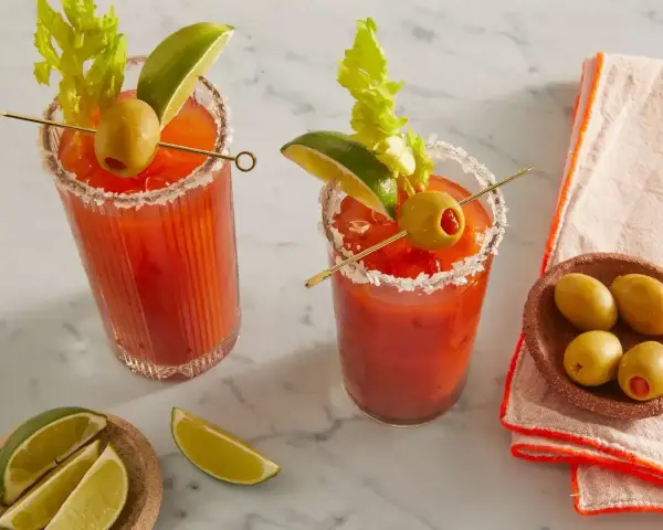 Dwa Bloody Mary: jedno na soku pomidorowym, drugie na passacie. Oba ozdobione łodygą selera, limonką i oliwką.