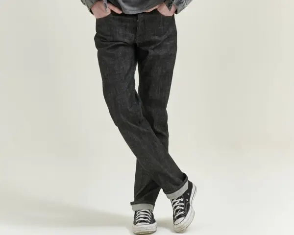 Uomo con jeans scuri e sneakers, che incarnano il comfort fit significato di libertà di movimento e stile casual.