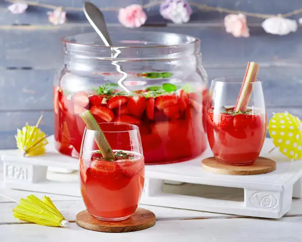 Erfrischende Rhabarber Bowle mit Erdbeeren und Minze, garniert mit Rhabarberstücken. Perfekt für den Sommer!