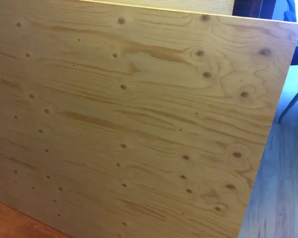 En stor skiva **betsa plywood** med tydliga ådringar och kvistar. Perfekt för ett rustikt projekt.