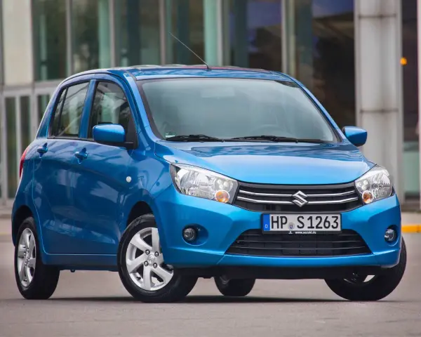 Niebieski Suzuki Celerio stoi przed nowoczesnym budynkiem.