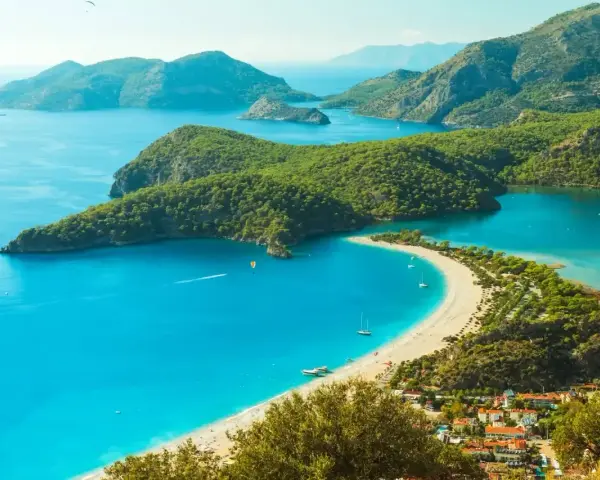 Turcja zachwyca turkusowym morzem i zielonymi wzgórzami. Widok na zatokę z plażą i górami.