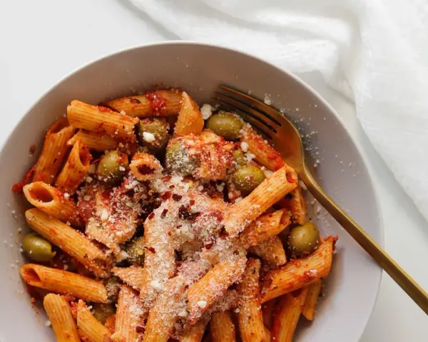 Penne z sosem pomidorowym, oliwkami i startą mozzarellą, posypane płatkami chili. Idealny makaron z mozzarellą na szybki obiad.