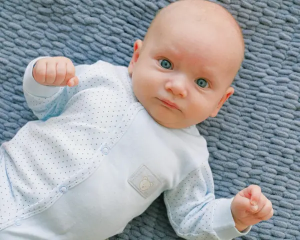 Niebieskie oczy niemowlaka patrzą wprost. Cudowny widok, kiedy dziecko przesypia noc.
