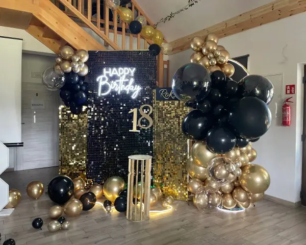 Elegancka ścianka do zdjęć na 18 urodziny z napisem "Happy Birthday" i liczbą 18, ozdobiona złotymi i czarnymi balonami.