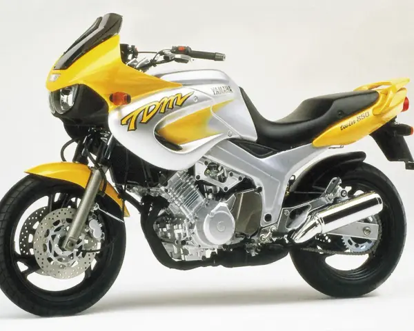 Żółto-srebrny motocykl Yamaha TDM 850 z charakterystycznym napisem "TDM" na baku. Gotowy na przygodę!
