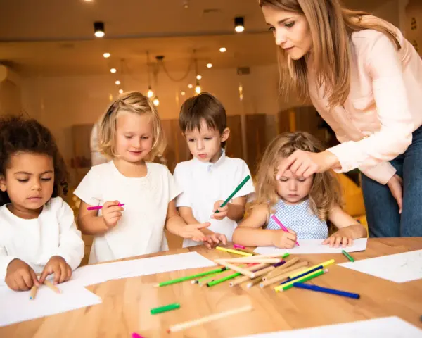 Nauczycielka wspiera dzieci w kreatywnym rysowaniu, promując edukację alternatywną.