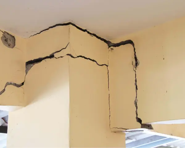 Détail d'une **micro fissure maison** sur un coin de mur en béton, révélant la structure interne.