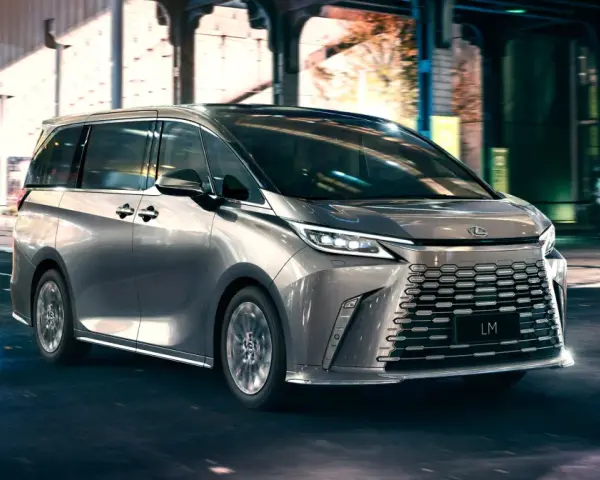 Srebrny van Lexus LM 350h na nocnej ulicy z rozmytym tłem.