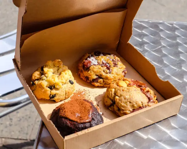 Vier köstliche, hausgemachte Cookies in einer Pappschachtel – die besten Cookies Berlins, bereit zum Genießen.