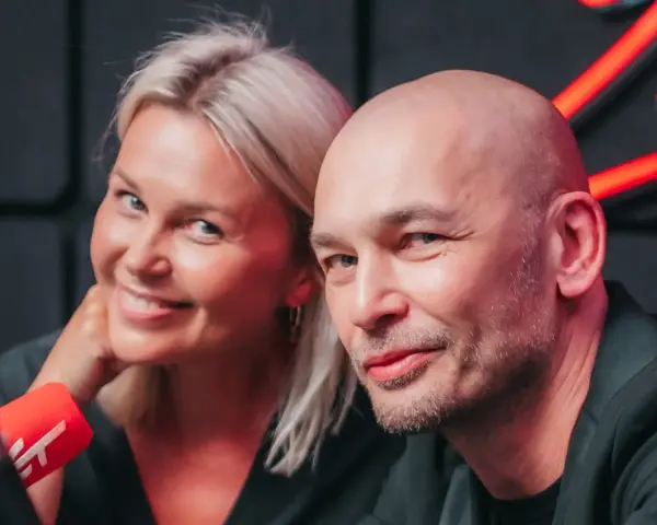 Tomasz Wygoda z żoną i dziećmi, uśmiechnięci przed mikrofonem.
