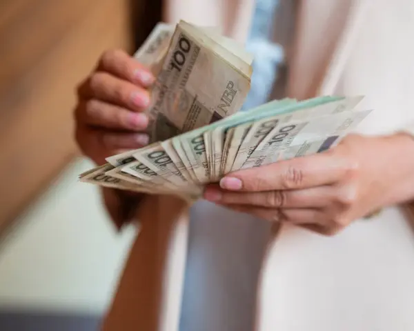 Dłonie liczą banknoty 100 zł. Zastanawiasz się, ile bierze komornik za alimenty?