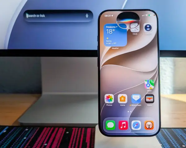 Ein iPhone zeigt Widgets für Wetter, Uhr und Kamera. Die Frage "was kann Siri alles" wird durch die vielen Apps und die Suchleiste auf dem iMac im Hintergrund angedeutet.