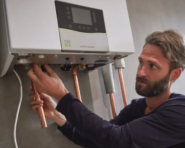 Installazione di una caldaia. Si sente il rumore dell'acqua che scorre mentre un tecnico collega i tubi di rame.