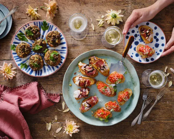 En härlig uppdukning med olika tapas recept. Små bruschettas med tomat, prosciutto och ost, samt fyllda champinjoner. Perfekt för en festlig stund!