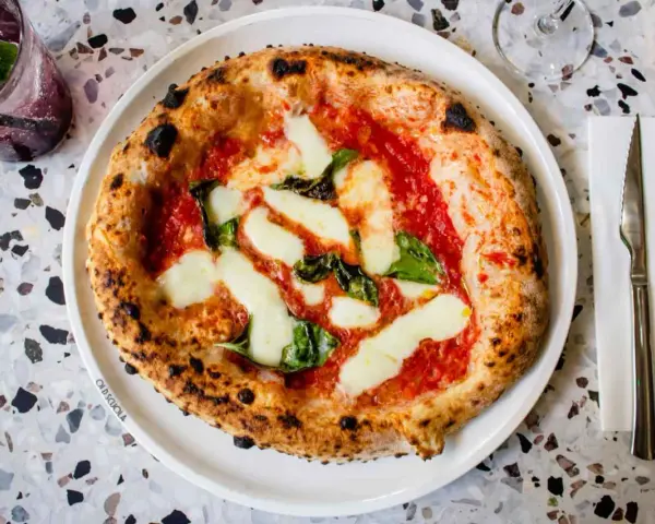 Pizza Margherita: darauf sind Tomatensauce, Mozzarella und frische Basilikumblätter.