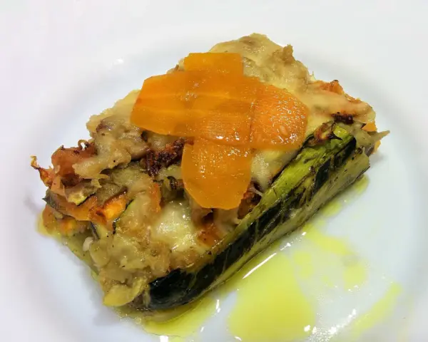 Deliciosa lasaña de verduras sin pasta, con capas de calabacín, zanahoria y queso fundido, servida en un plato blanco.
