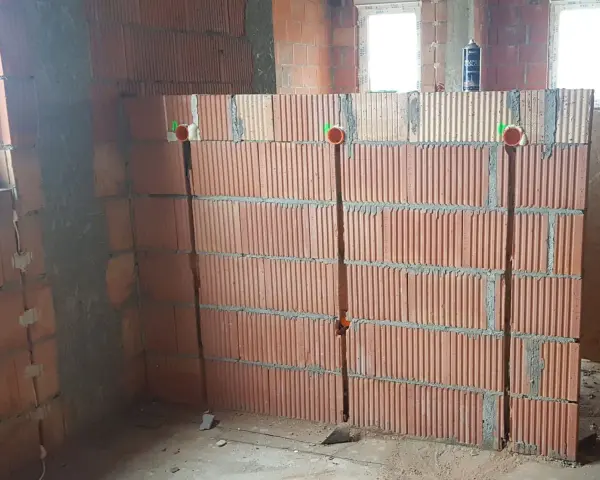 Wykonano bruzdowanie pod kable w ścianie z pustaków ceramicznych. Widoczne są puszki instalacyjne.