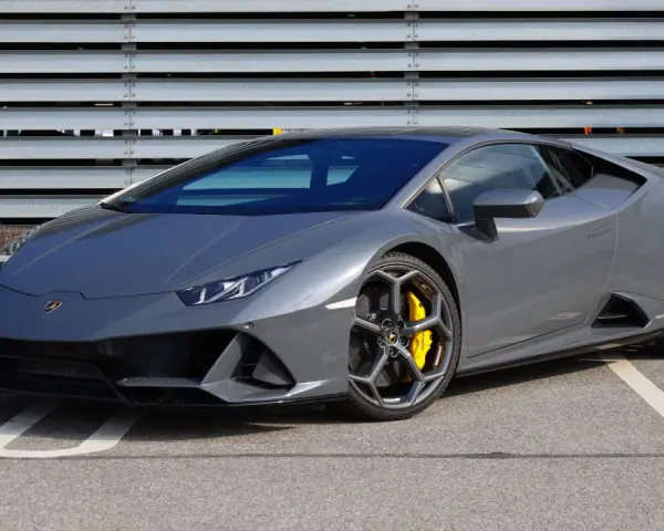 Szary Lamborghini Huracan z żółtymi zaciskami hamulcowymi na tle metalowej ściany.
