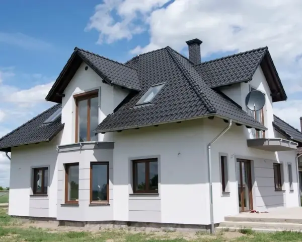 Nowoczesny dom z białymi boniami na elewacji, czarnym dachem i brązowymi oknami.