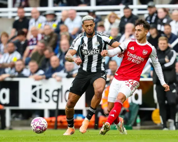 Piłkarze Newcastle i Arsenal walczą o piłkę na boisku. Intensywna akcja podczas meczu.