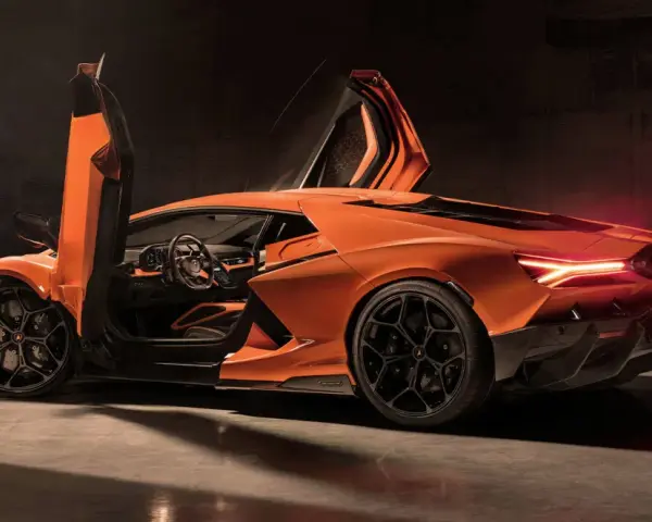 Pomarańczowy Lamborghini Revuelto z otwartymi drzwiami, ukazujący sportowe wnętrze i agresywną sylwetkę.