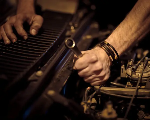 Ręce mechanika naprawiające silnik samochodu kluczem.