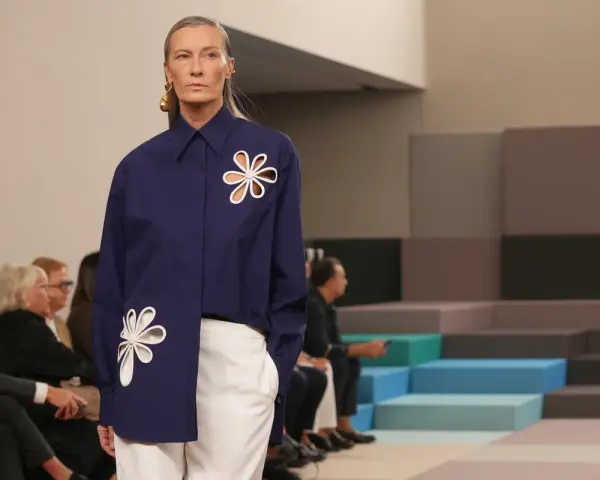 Modella con camicia blu Fendi e pantaloni bianchi, un'icona di stile che racconta la sua storia.