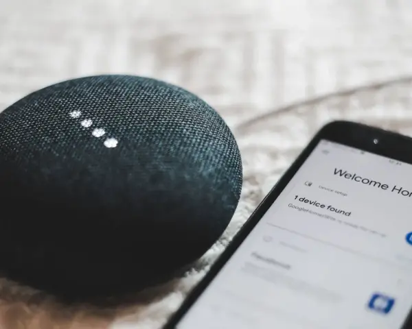 A smart speaker and phone display "Welcome Home" and "1 device found," showcasing modern iot design for a connected home.