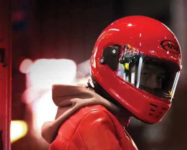 Un motociclista indossa un casco integrale rosso brillante, pronto per la strada.