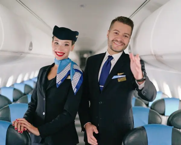 Uśmiechnięta stewardessa i steward w uniformach LOT-u, gotowi do lotu. Marzysz, jak zostać stewardessą? To początek Twojej przygody!