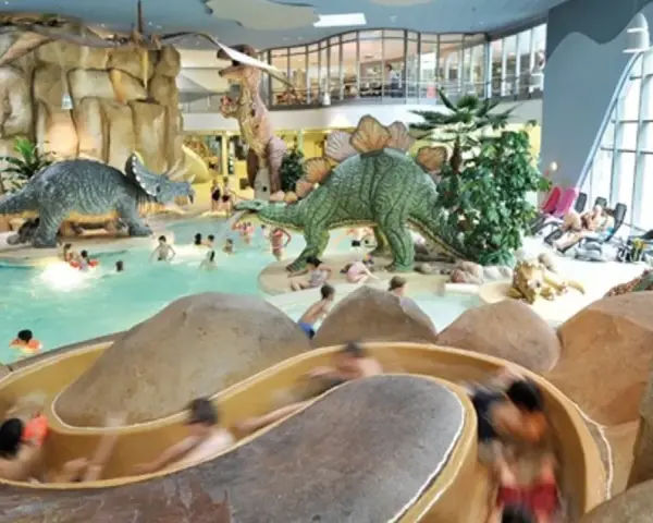 Kinder planschen im Dino-Bad, ein perfektes Ziel für die Herbstferien in Hamburg. Rutschen und Dinosaurier sorgen für Spaß.