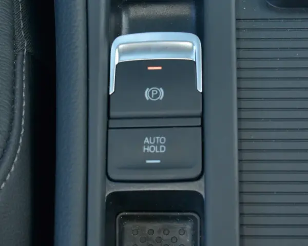 Przycisk AUTO HOLD w samochodzie. To funkcja, która automatycznie utrzymuje pojazd w miejscu po zatrzymaniu.