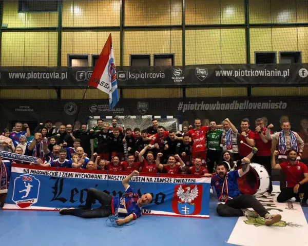 Drużyna KPR Legionowo świętuje zwycięstwo, trzymając transparent z herbem i hasłem.