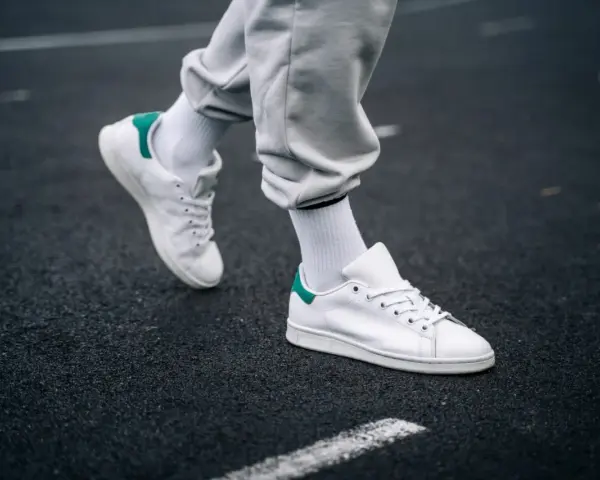 Un paio di sneakers bianche con dettagli verdi, simbolo di stile e comfort. Il loro significato va oltre la moda, rappresentando libertà di movimento.