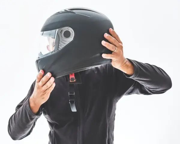 Persona indossa un casco integrale nero, pronto per un giro in moto.