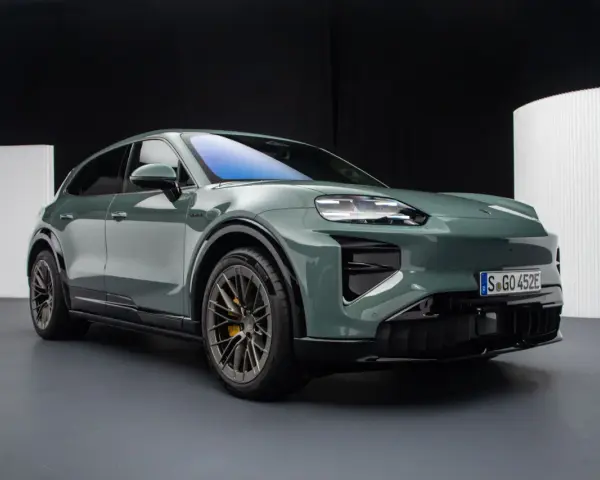 Zielony elektryczny Porsche Macan na ciemnym tle.