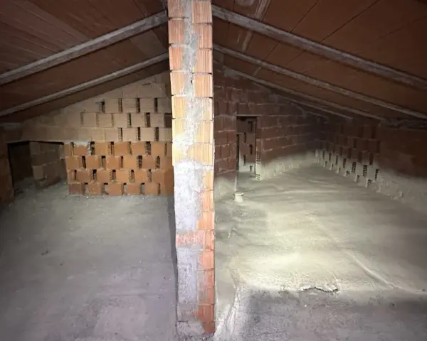 Sottotetto in costruzione con pareti in mattoni e tetto in legno. La lana di roccia a cosa serve? Qui si vede l'isolamento termico e acustico.