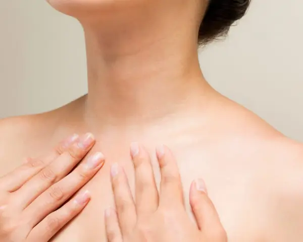 Mains caressant le cou et le décolleté, une invitation à muscler son cou pour une posture élégante.