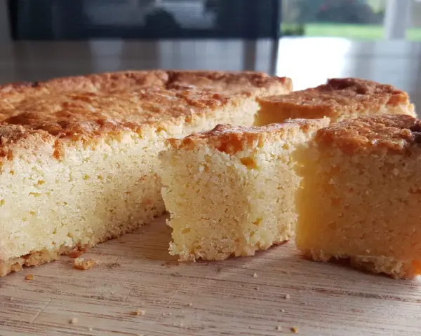 Un delicioso pastel bretón, dorado y esponjoso, cortado en porciones sobre una tabla de madera.