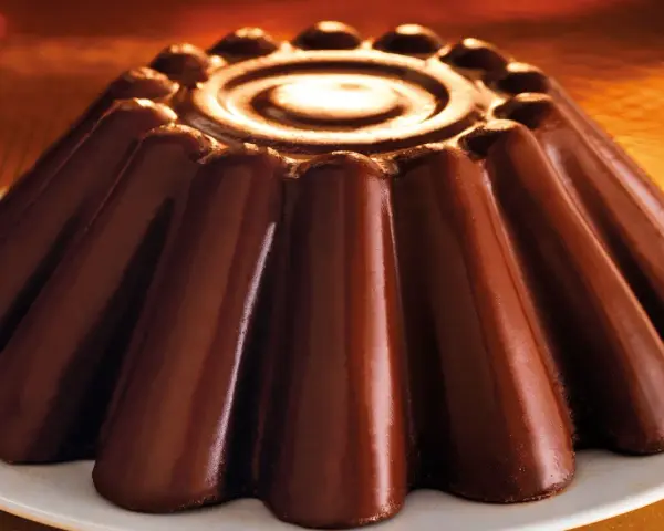 Budino al cioccolato lucido e invitante, con un disegno a spirale al centro e un bordo decorato.