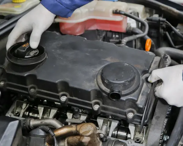 Mechanik w białych rękawiczkach sprawdza silnik. Może to być związane z nieszczelna odma objawy.