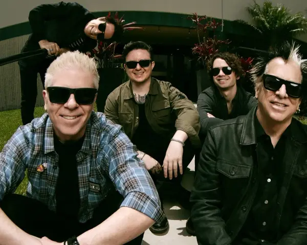 Les membres de The Offspring posent ensemble, souriants et portant des lunettes de soleil. Le groupe semble prêt pour une nouvelle aventure musicale.