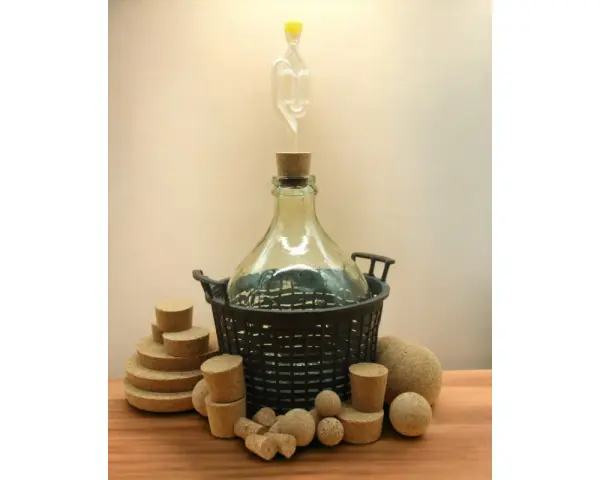 Duża butla z rurką fermentacyjną i korkami, gotowa, by jak pobudzić wino do fermentacji.