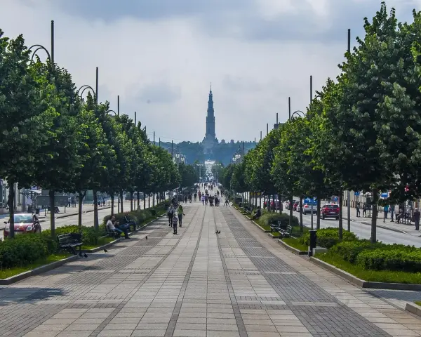 Aleja z drzewami i bazyliką w tle. Spacer po alei to jedne z częstochowskich atrakcji dla dzieci, które mogą podziwiać architekturę i poczuć atmosferę miasta.